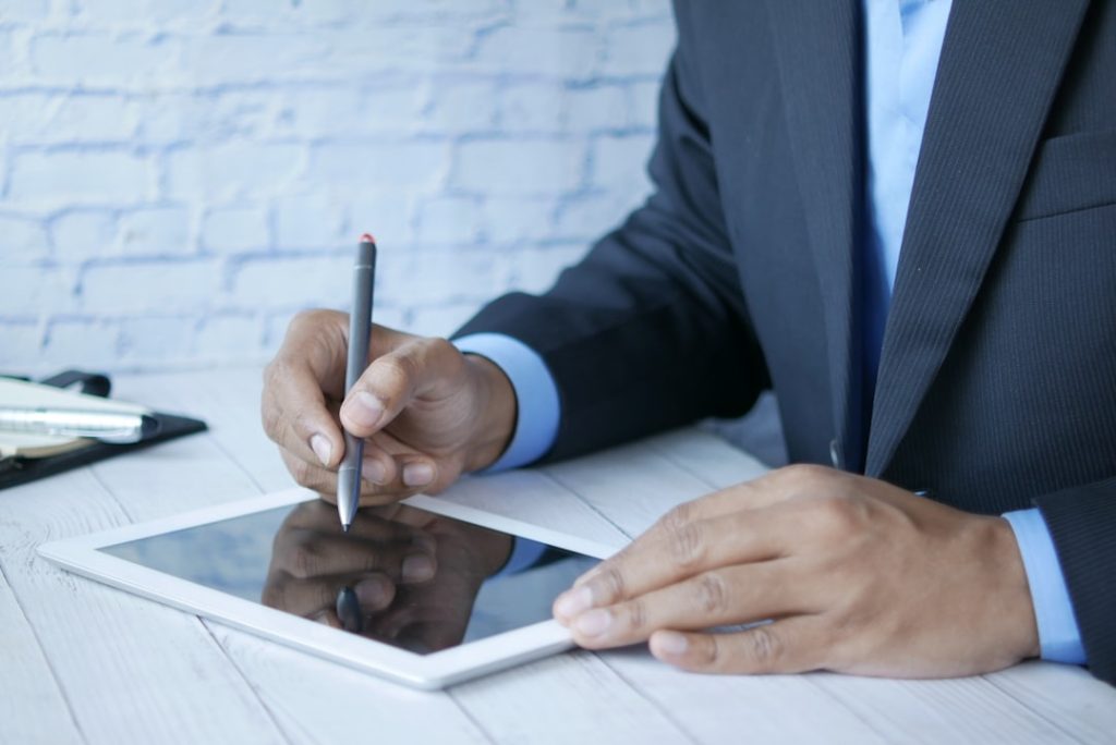 a-man-in-a-suit-writing-on-a-tablet-b0q9akkv6mk